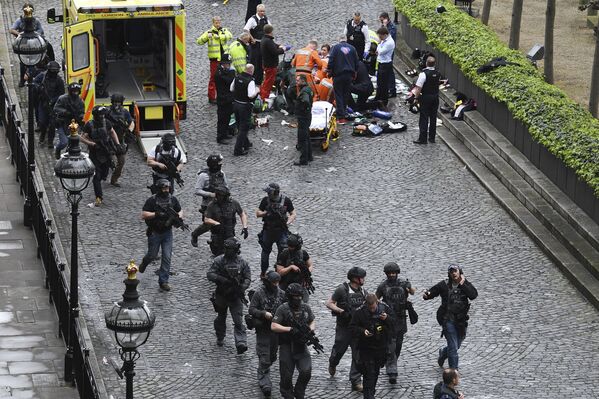 Вооруженные сотрудники полиции проходят мимо криминалистов и сотрудников чрезвычайных служб, которые работают на месте стрельбы у Вестминстерского моста в Лондоне - Sputnik Грузия