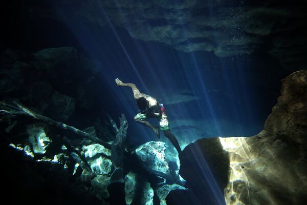 Работник пещеры Poco Azul (Голубой колодец) ныряет в поисках туристического брошенного имущества, в преддверии Всемирного дня воды, в Баия, Бразилия - Sputnik Грузия