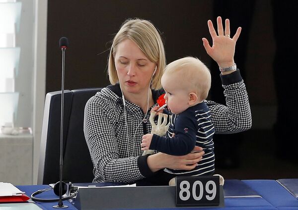 Депутат Европейского парламента от Швеции Житте Гутеланд держит ребенка, участвуя в голосовании в Европарламенте в Страсбурге, Франция - Sputnik Грузия