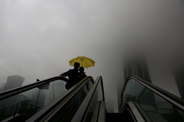 Один из туманных дней в Шанхае: на фото - женщины с зонтиками направляются к мосту в финансовом районе Пудун - Sputnik Грузия
