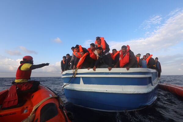 Испанские спасатели помогают мигрантам, плывущим на деревянном судне в Средиземном море у побережья Ливии - Sputnik Грузия