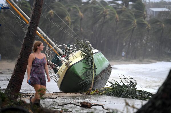 Жительница Австралии проходит мимо яхты, которая была выброшена на берег во время циклона Дебби в городе Квинсленд. Сила ветра во время стихийного бедствия в Австралии достигала 263 км в час - Sputnik Грузия
