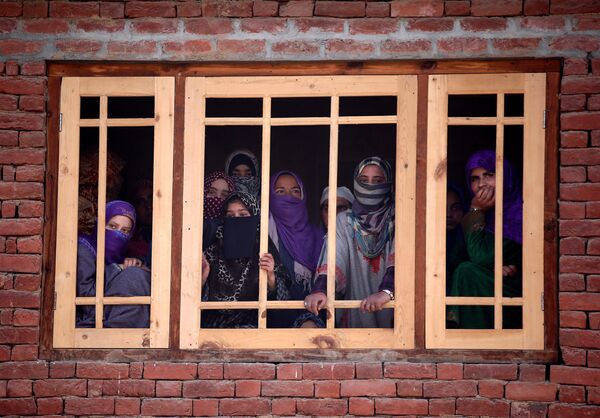 Женщины-мусульманки смотрят из окна на похороны Райеда Ахмада Вани в деревне Беллоу на юге Кашмира. По сообщениям СМИ, Райед Ахмад Вани был убит в Падгампоре во время столкновения с индийскими силами безопасности - Sputnik Грузия