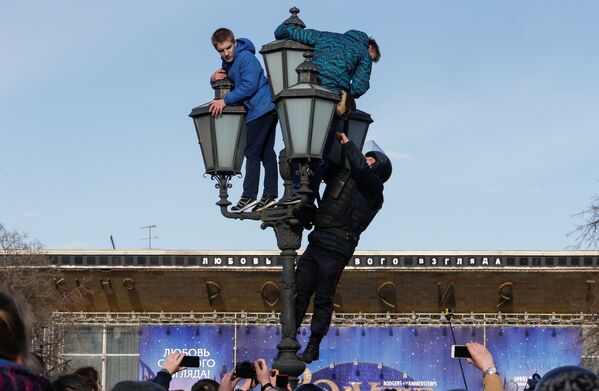 Сотрудник правоохранительных органов взбирается на фонарный столб, чтобы задержать участников несанкционированного митинга против коррупции в Москве, Россия - Sputnik Грузия