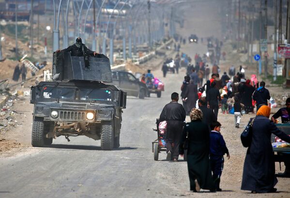 Военный автомобиль Иракских сил безопасности проезжает мимо местных жителей, покидающих свои дома в старом Мосуле, из-за продолжающихся боев между правительственными силами и боевиками Исламского государства - Sputnik Грузия