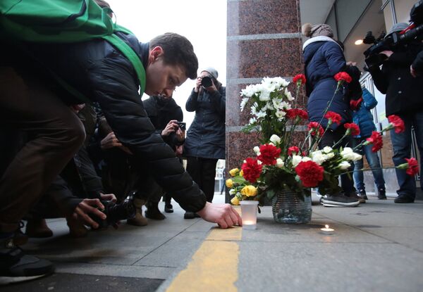Люди возлагают цветы и зажигают свечи у входа на станцию метро Спасская в память о погибших в результате взрывов в метрополитене Санкт-Петербурга - Sputnik Грузия