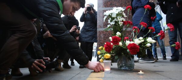 Люди возлагают цветы и зажигают свечи у входа на станцию метро Спасская в память о погибших в результате взрыва в метрополитене Санкт-Петербурга - Sputnik Грузия