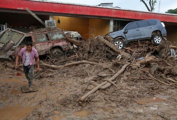 Человек идет по разрушенной улице в Мокоа, Колумбия. Селевой поток принес в город огромные камни, грязь, мусор и сломанные деревья - Sputnik Грузия