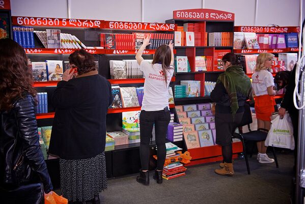 Люди выбирают книги на полках одного из выставочных стендов - Sputnik Грузия