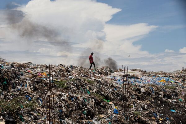 Мужчина идет по мусорной свалке в городе Кисуму, Кения - Sputnik Грузия