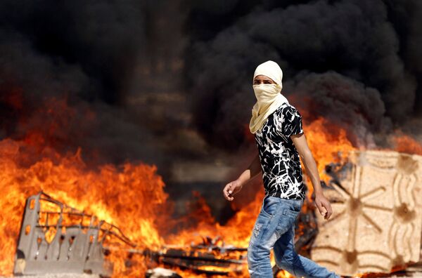 Палестинский демонстрант на фоне пожарища во время столкновений с израильскими войсками в поддержку палестинских заключенных, объявивших голодовку в израильских тюрьмах в деревне на Западном берегу Бейта, возле Шхема - Sputnik Грузия