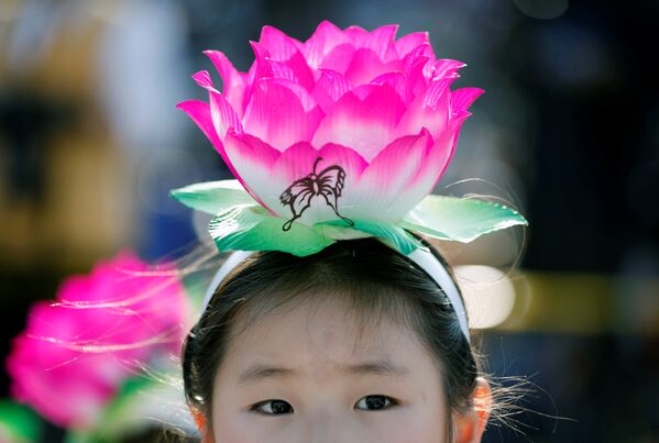 Ребенок с фонариком на голове в виде цветка лотоса перед началом праздничного парада в Сеуле - Sputnik Грузия