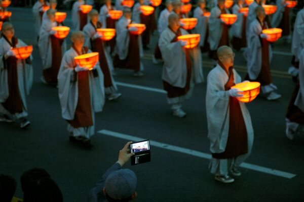 Человек фотографирует буддистских монахов, идущих по улицам Сеула с фонариками во время парада в честь дня рождения Будды - Sputnik Грузия