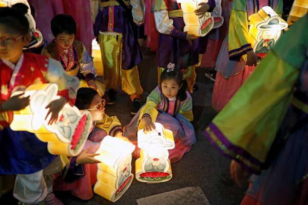 Дети - участники праздничного шествия с фонариками, отдыхают во время проведения красочного парада в честь дня рождения Будды в Сеуле - Sputnik Грузия