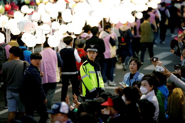 Полицейский охраняет буддистов, участвующих в праздничном параде в Сеуле по случаю Дня рождения Будды - Sputnik Грузия