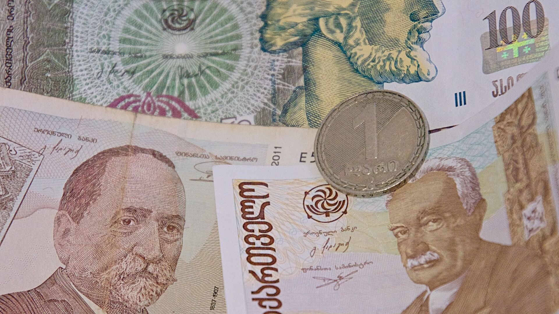 Монета достоинством в 1 лари на банковских купюрах различного номинала - Sputnik Грузия, 1920, 16.09.2022