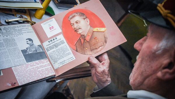 Николоз Чарашвили держит в руках альбом с изображением Сталина - Sputnik Грузия