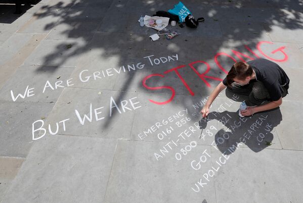 Человек пишет на асфальте анти-террористическое обращение в центре города Манчестер после теракта на стадионе - Sputnik Грузия