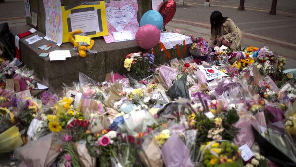 Женщина в центре Манчестера возлагает цветы к мемориалу жертв террористического акта на стадионе Манчестер Арена - Sputnik Грузия