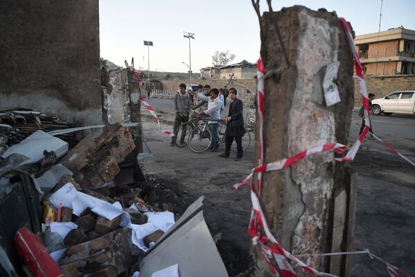 Люди стоят возле поврежденого здания неподалеку от места взрыва грузовой автомашины в Кабуле, Афганистан - Sputnik Грузия