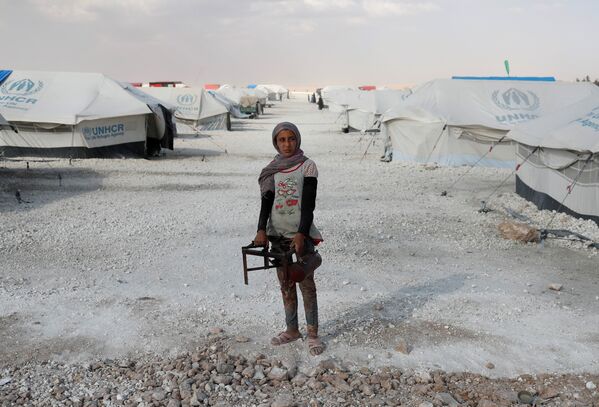 Подросток идет по лагерю для беженцев, покинувших свои дома в захваченной исламистами Ракке, держа в руке кушетку. Айн-Исса, Сирия - Sputnik Грузия
