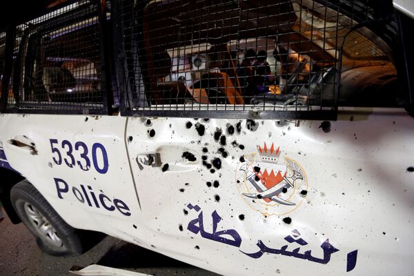 Следы и повреждения от осколков на кузове патрульной полицейской машины, полученные в результате взрыва шрапнели в деревне Дираз, Бахрейн - Sputnik Грузия