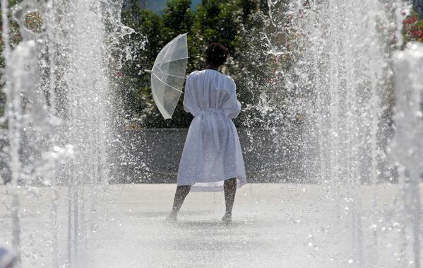 Женщина спасается от летнего солнца под брызгами фонтана в середине жаркого июньского дня в Париже, Франция - Sputnik Грузия
