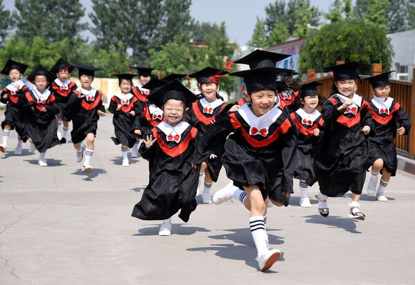 Дети в костюмах выпускников бегают во время церемонии окончания детского сада в детском саду в Хандане, провинция Хэбэй, Китай - Sputnik Грузия