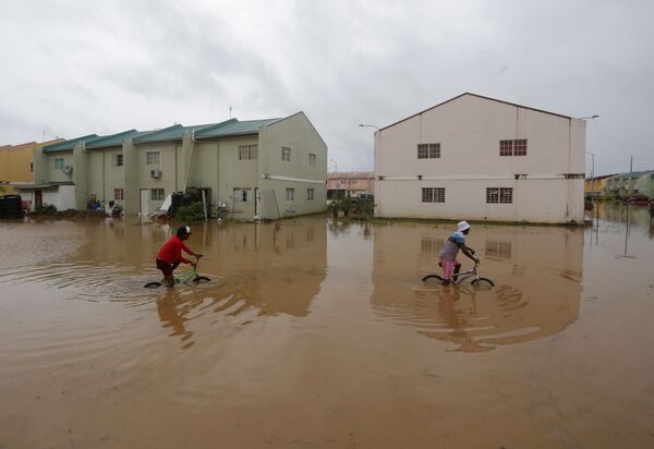Дети катаются на велосипедах по затопленной улице после тропического шторма Брет в Оропуне, Тринидад и Тобаго - Sputnik Грузия