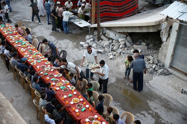 Люди собираются на Ифтар, организованный Фондом Адалех, среди поврежденных зданий во время священного месяца Рамадан в осажденном районе Доума в Дамаске, Сирия - Sputnik Грузия