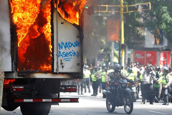 Сотрудники сил безопасности у правительственного грузовика, который был подожжен во время митинга против правительства президента Венесуэлы Николаса Мадуро в Каракасе, Венесуэла - Sputnik Грузия