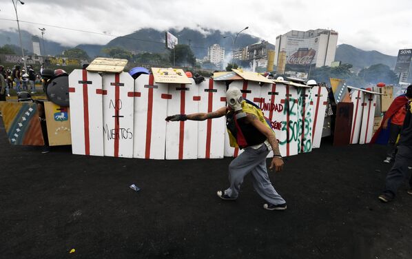 Оппозиционные активисты укрываются за щитами во время столкновений с полицией в ходе антиправительственных демонстраций против президента Венесуэлы Николаса Мадуро. На фото - действие происходит перед военно-воздушной базой Франсиско-де-Миранды в Каракасе, недалеко от места, где молодой протестующий был застрелен полицией несколько дней назад - Sputnik Грузия
