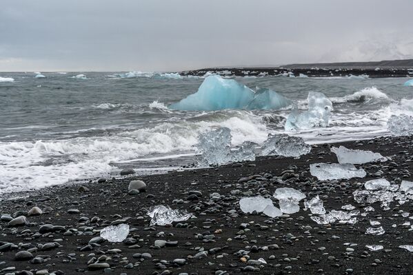 Йёкюльсаурлоун, Исландия. Черный песок, образованный в результате вулканических извержений, на этом исландском пляже прекрасно контрастирует с белыми кусками льда - Sputnik Грузия