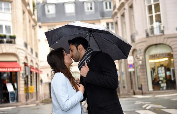Пара, целуясь, укрывается под зонтиком на парижской улице - Sputnik Грузия