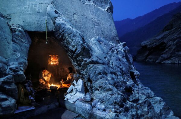 Индуистские священники сидят в пещере во время вечерних молитв на берегах реки Ганг, Индия - Sputnik Грузия