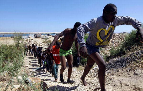 Спасенные мигранты идут по побережью Гараболи, к востоку от Триполи, Ливия - Sputnik Грузия