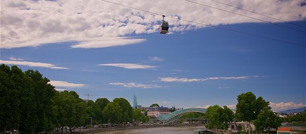 Кабинка канатной дороги с туристами проезжает над набережной Тбилиси и рекой Кура Кабинка канатной дороги с туристами проезжает над набережной Тбилиси и рекой Кура - Sputnik Грузия