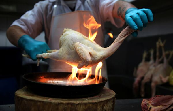 Мясник обрабатывает курицу, сжигая ее перья, на Центральном рынке Лимы, Перу - Sputnik Грузия