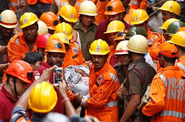 Спасатели несут тело погибшего после того, как часть здания рухнула в Калькутте, Индия - Sputnik Грузия