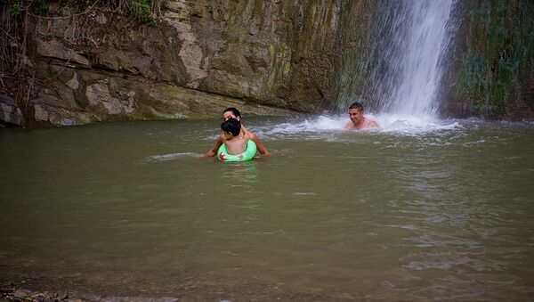 Семья купается в водопаде в летнюю жару в тбилисском Ботаническом саду - Sputnik Грузия