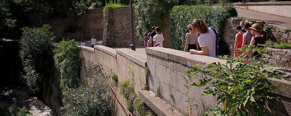 Туристы идут по центральной аллее тбилисского Ботанического сада, с которой открывается вид на реку Цавкисисцкали - Sputnik Грузия