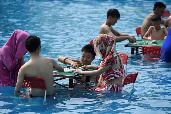 Люди играют в маджонг, сидя в воде в аквапарке в жаркий летний день в Чунцине, Китай - Sputnik Грузия