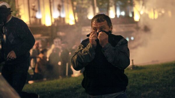 Участник акции протеста грузинской оппозиции закрывает лицо от слезоточивого газа во время беспорядков на проспекте Руставели в Тбилиси, 2011 год - Sputnik Грузия