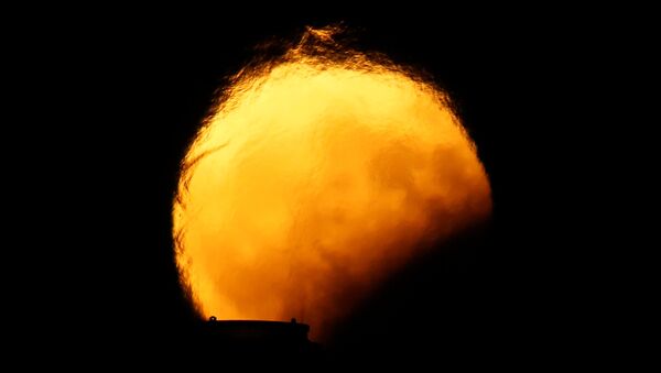Луна во время частичного лунного затмения искажается горячим воздухом, поднимающимся из дымовых труб электростанции в Делимаре, за пределами деревни Марсаклокк, Мальта - Sputnik Грузия