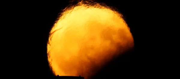 Луна во время частичного лунного затмения искажается горячим воздухом, поднимающимся из дымовых труб электростанции в Делимаре, за пределами деревни Марсаклокк, Мальта - Sputnik Грузия