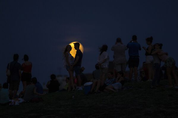 Люди смотрят на восходящую Луну во время частичного лунного затмения на вершине холма в парке Тио Пио в Мадриде - Sputnik Грузия