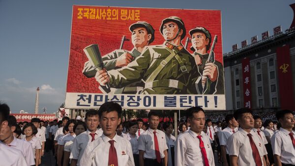 Люди несут плакат во время митинга в поддержку позиции Северной Кореи против США на площади Ким Ир Сена в Пхеньяне - Sputnik Грузия