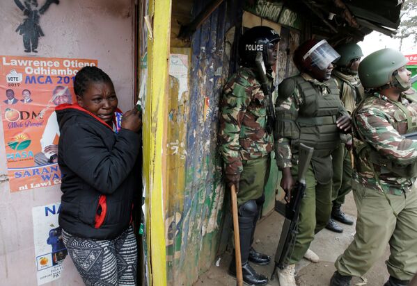 Массовые беспорядки начались в нескольких кенийских городах после оглашения результатов президентских выборов. На фото - женщина плачет, стоя за полицейскими, во время столкновений между сторонником лидера оппозиции Раилы Одгинга и полицейскими в трущобах Киберы в Найроби - Sputnik Грузия