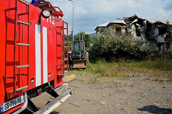 Пожарные на месте взрыва на фоне разрушенного дома у газозаправочной станции - Sputnik Грузия
