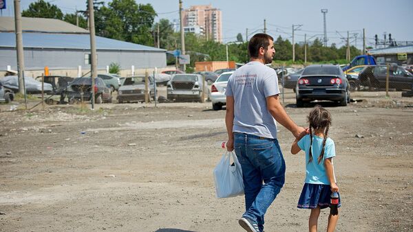 Отец с дочерью идет вдоль авторынка на Исани после пожара - Sputnik Грузия